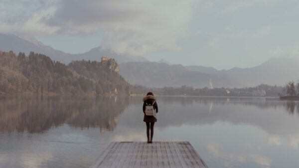 woman standing beside body of calm water