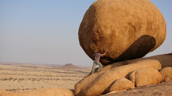 man standing beside rock formation