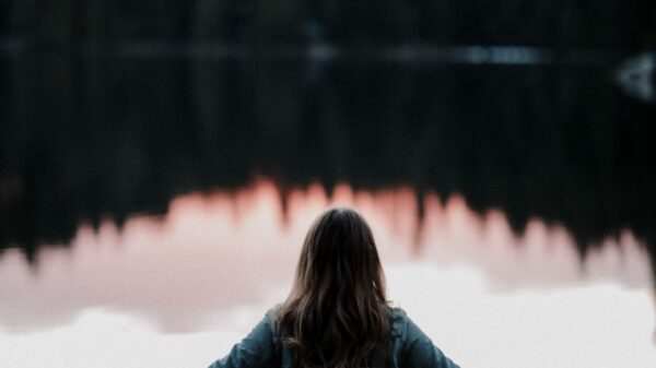 woman standing while facing on body of water