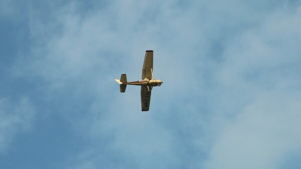 brown airplane flying under white clouds