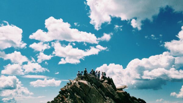 people on rock formation under white cloudy sky