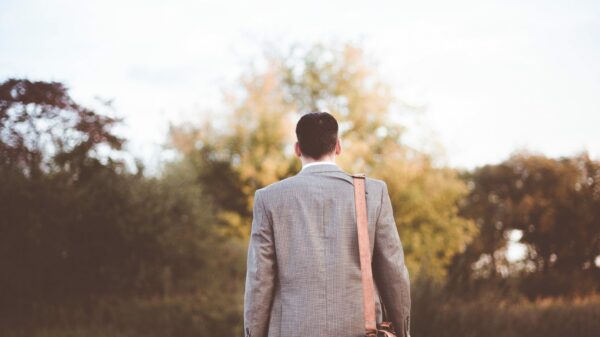 man wearing gray coat standing near road during daytime