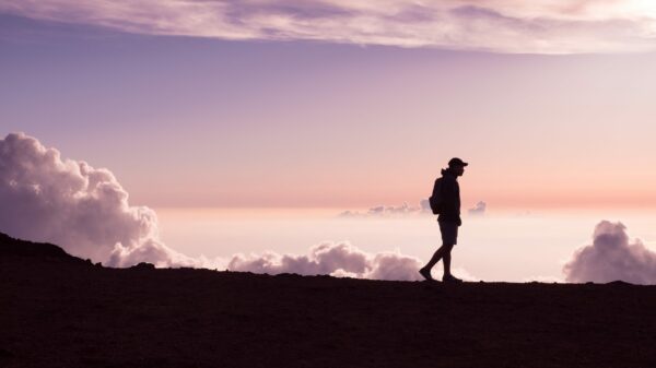 silhouette of person walking under white clouds