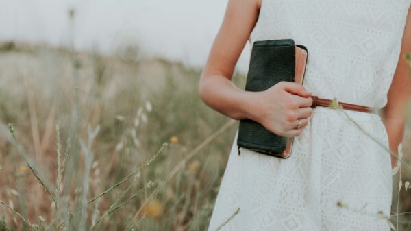 woman in white sleeveless dress holding book