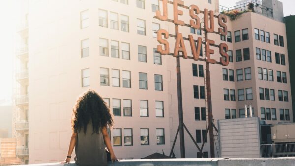 woman in gray top sitting on a building's edge