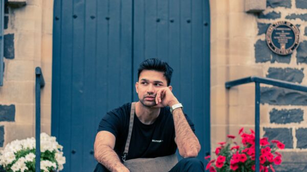 man in black crew neck t-shirt and blue denim jeans sitting on gray concrete bench