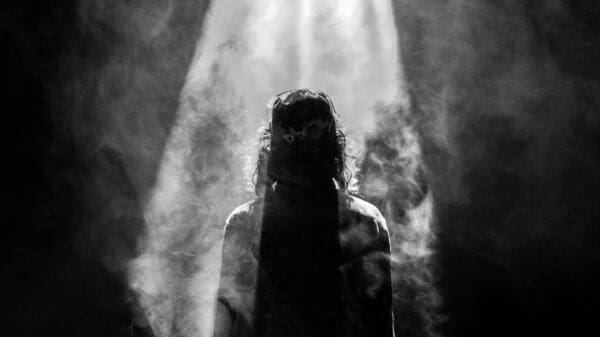 photograph of person facing opposite in smoky spotlight