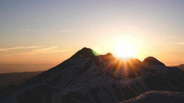 sun rays coming through mountain under orange sky