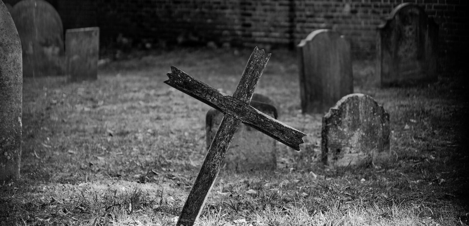 grayscale photo of cross on grass field