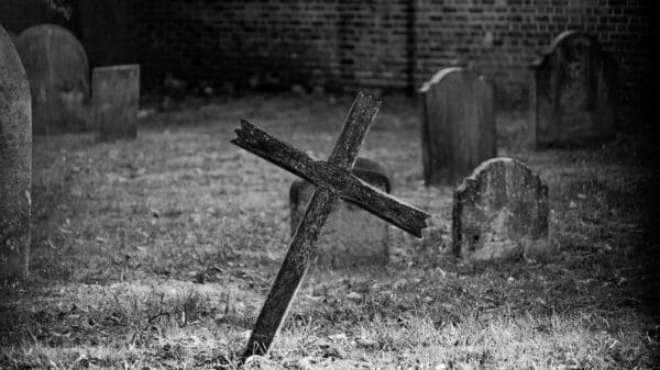 grayscale photo of cross on grass field