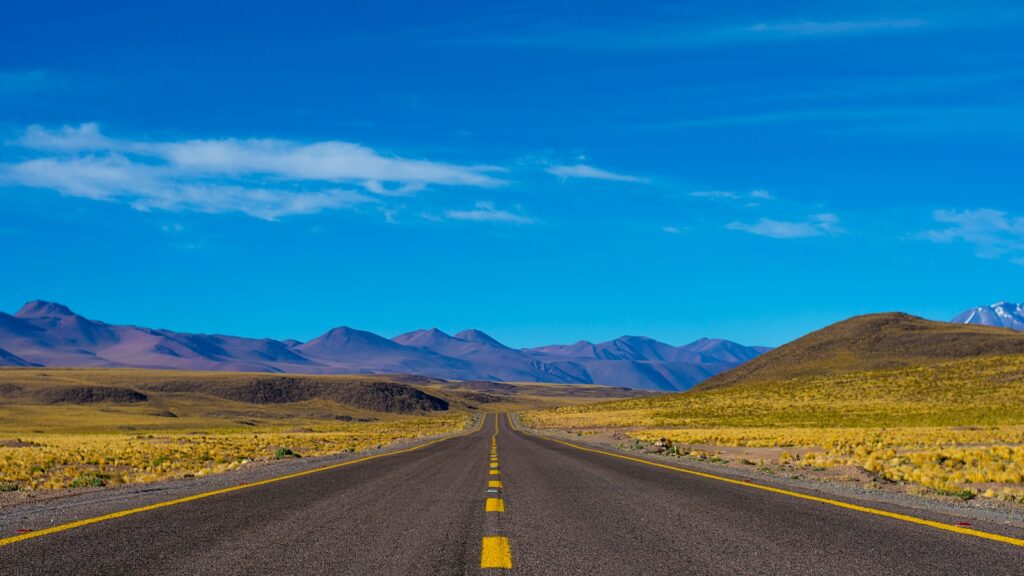 empty paved road near mountains during daytime