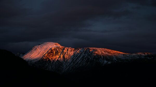a snow covered mountain under a cloudy sky