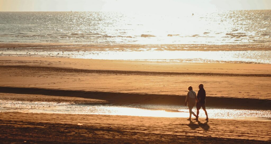 two person walking beside beach